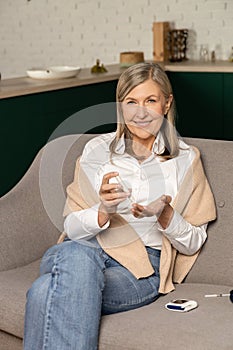 Smiling good-looking woman with blood sugar testing stick