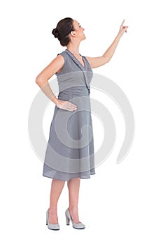 Smiling gorgeous woman in classy dress pointing out direction