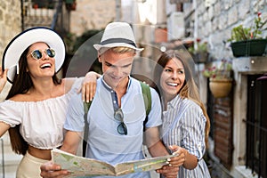 Smiling gorup of friends with map. Tourism, travel, leisure, holidays and friendship concept