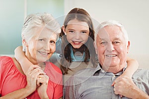 Smiling granddaughter embracing her grandparents in living room