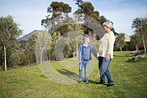 Smiling granddaughter and grandmother standing together in garden