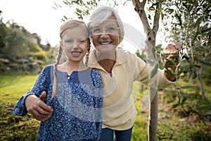 Smiling granddaughter and grandmother standing together in garden