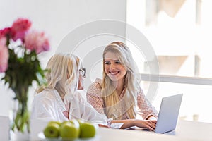 Smiling granddaughter and grandmother using laptop computer