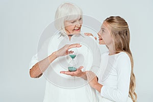 smiling granddaughter hugging grandmother with hourglass