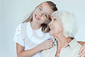 smiling granddaughter hugging grandmother and looking