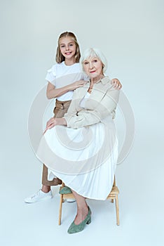 smiling granddaughter hugging grandmother on stool