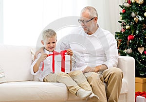 Smiling grandfather and grandson with gift box