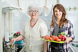 Smiling grandmother with granddaughter cooking in the kitchen.