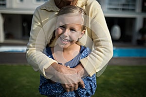 Smiling grandmother and granddaughter embracing each other in garden