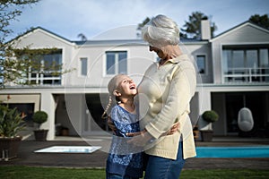 Smiling grandmother and granddaughter embracing each other in garden