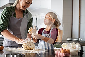 Smiling grandmother and happy child kneading dough photo