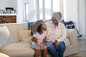 Smiling grandmother interacting with granddaughter in living room