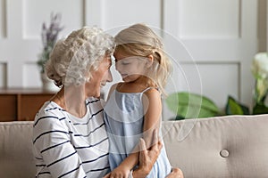 Smiling grandmother relax cuddling with small granddaughter