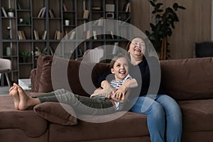Smiling grandmother and teen granddaughter relax on couch