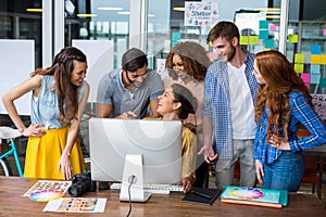 Smiling graphic designers interacting with each other while working at desk