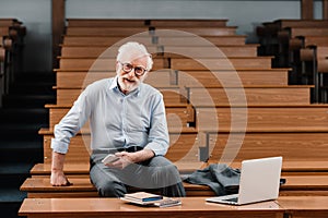 smiling grey hair professor sitting in empty photo