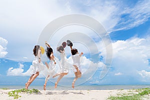 Smiling group asian woman wearing fashion white dress summer walking the sandy sea beach, blue sky sunshine background. Happy