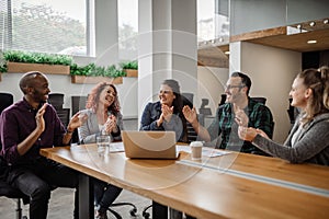 Smiling group of businesspeople clapping together during an office meeting