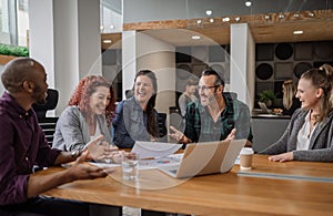 Smiling group of businesspeople laughing together in modern office work space