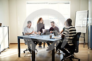 Smiling group of designers talking together around an office tab