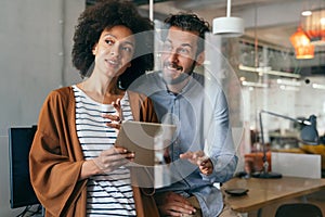 Smiling group of diverse businesspeople going over paperwork together, working in corporate office