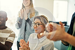 Smiling group of diverse colleagues clapping during an office me