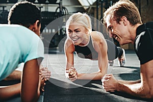 Smiling friends planking together during a gym workout session photo