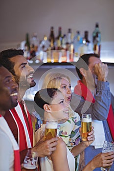 Smiling group of friends having beer while watching match