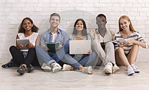 Smiling group of international students studying over white brick wall