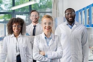 Smiling Group Of Scientists In Modern Laboratory With Female Leader, Mix Race Team Of Scientific Researchers In Lab