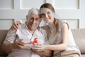 Smiling grownup daughter congratulate senior father at home