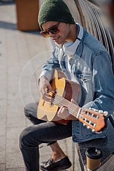 Smiling guitarist in hat playing song on the street