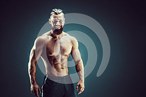 Bodybuilder posing. Fitness muscled man on dark background.