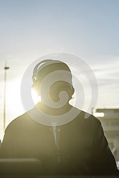 Smiling guy in casual leather jacket looking far in a music disco club outdoor - Millennial disc jockey wearing headphones  during