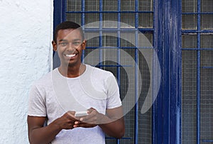 Smiling guy holding mobile phone outside