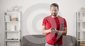 smiling guy in red tshirt chatting on mobile phone, shooping online