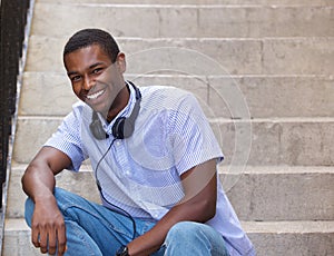 Smiling guy sitting on steps outside with headphones