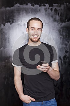 Smiling guy with smartphone typing SMS