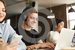 Smiling guy studying in college library, using laptop