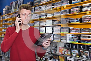 Smiling guy talking on mobile phone in shop