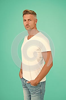 smiling guy with trendy hairstyle has colored graying hair and groomed face on turquoise background, mens beauty