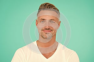 smiling guy with trendy hairstyle has colored graying hair and groomed face on turquoise background, personal care