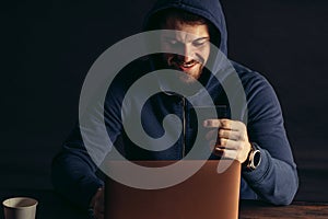 Smiling hacker man sit holding bank card