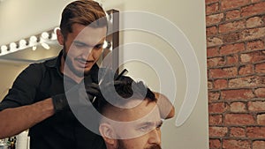 Smiling hairdresser cutting hair of client with scissors