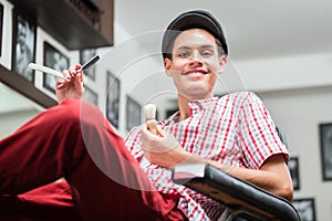 Smiling hairdresser holding razor and shaving brush