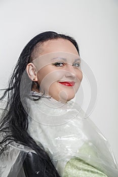 Smiling with half shaved head brunette woman with bright makeup in barber chair.