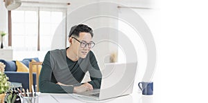 Smiling handsome asian businessman working remotely from home. He is webinar video conference