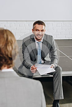 smiling handsome business coach sitting on stage during training