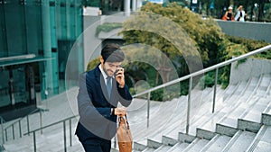 Smiling handsome business man looking at time while calling manager. Exultant.