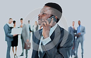 Smiling handsome business man using cell phone with colleagues in background.